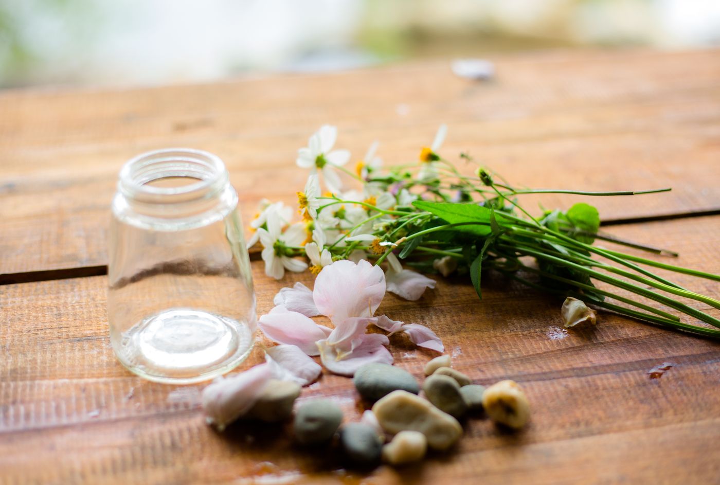 Wildflowers and pebbles arranged on a wooden table